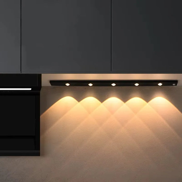 Motion-sensor LED light mounted under a kitchen cabinet illuminating the countertop for evening cooking