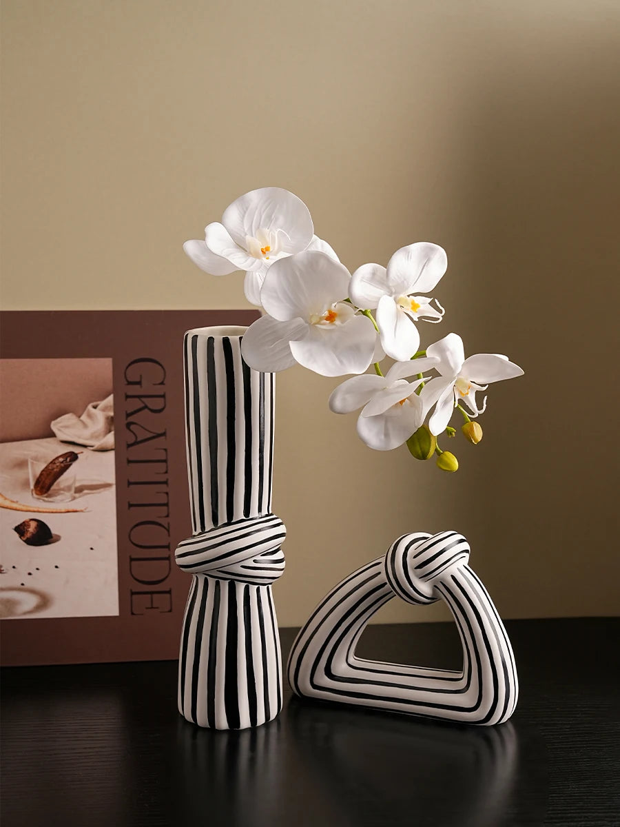 Black and white striped ceramic knot sculpture vase on a console table